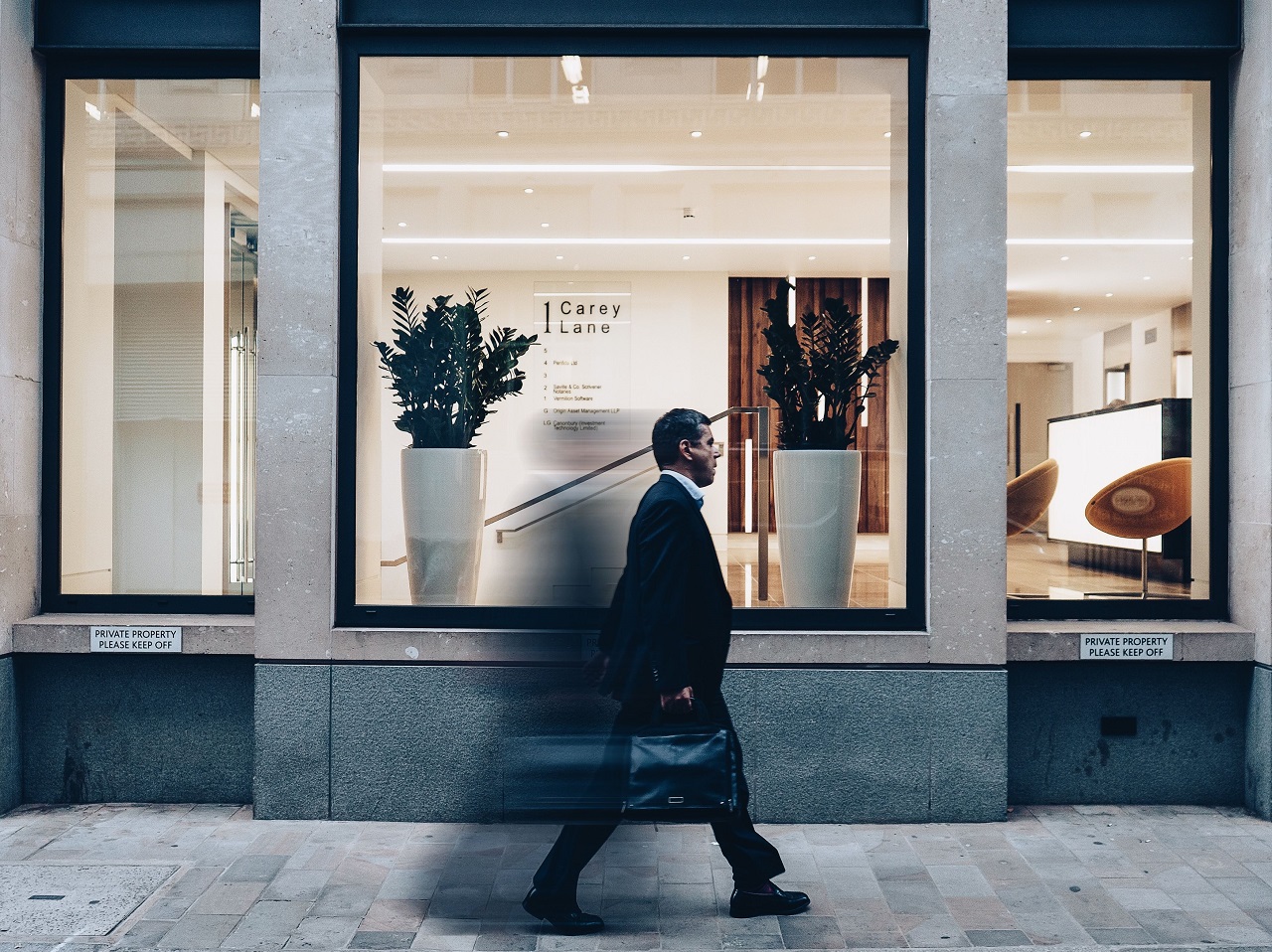 A lone walker moving through an urban environment of concrete and glass